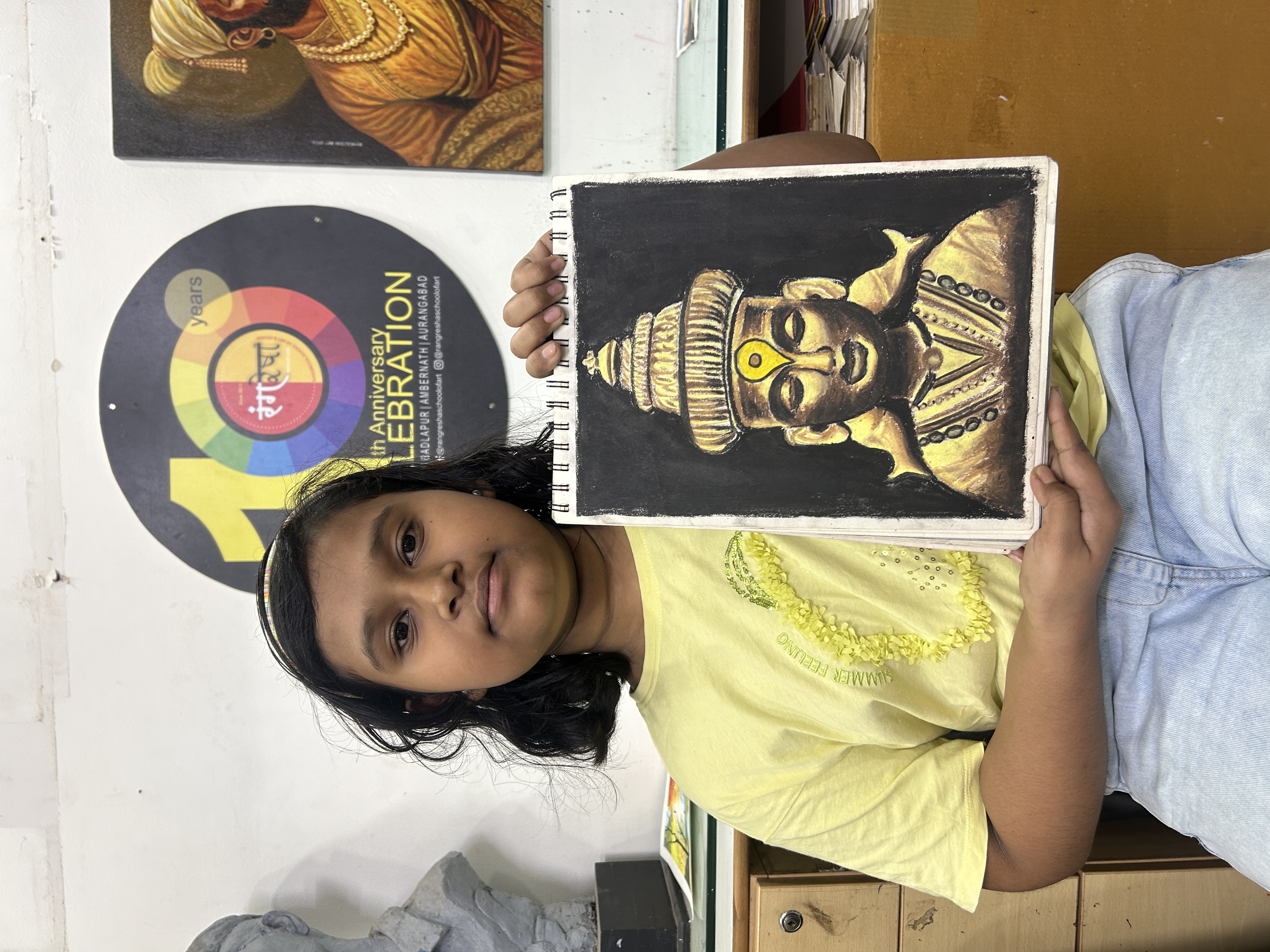 Rangresha student holding finished artwork